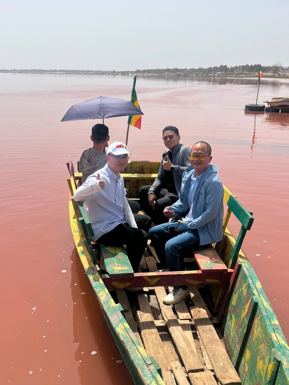 Groupe souriant dans une pirogue colorée sur le Lac Rose